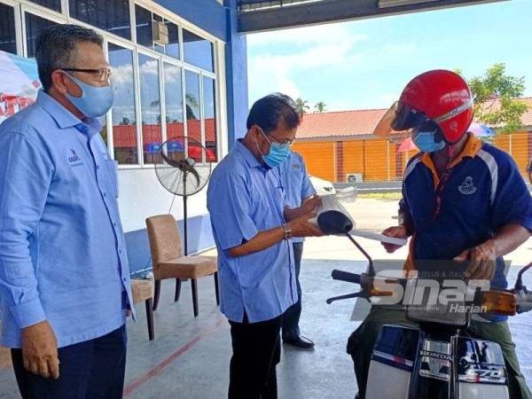 Che Abdullah (dua dari kiri) menyampaikan sumbangan Tabung Bantuan Bencana Banjir Padi KADA menerusi MAFI Prihatin secara pandu lalu di Pejabat PPK Kubang Sepat, Tendong di Pasir Mas pada Selasa.