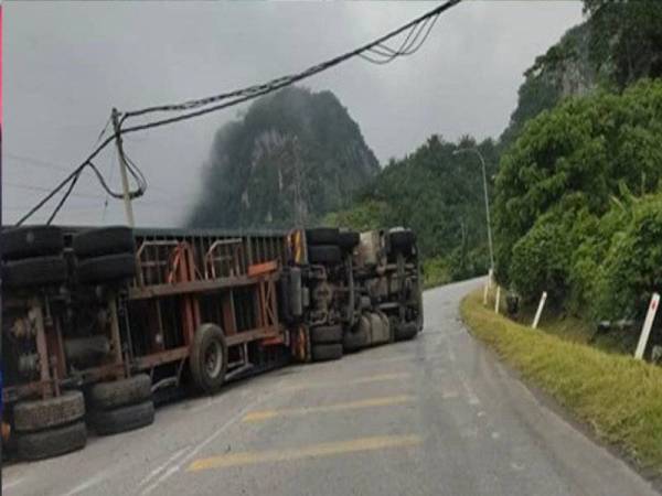 Sebuah lori kontena yang membawa muatan sarung tangan getah terbalik dan melintang di laluan di Kilometer Tiga Jalan Gua Musang-Kuala Krai, pagi Rabu.