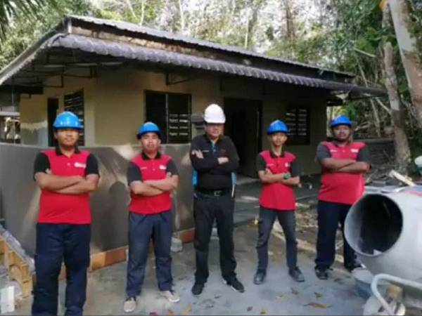 Khairul (tengah) ketika membantu memasang pendawaian elektrik di sebuah rumah masyarakat orang asli baru-baru ini.