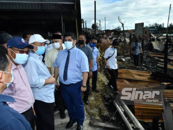 Hajiji (tiga dari kiri) melawat lokasi kebakaran yang memusnahkan 35 buah rumah di kawasan Kampung Meruntum, Putatan pada Isnin.