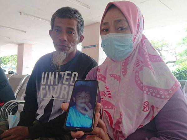 Rohana dan suaminya menunjukkan gambar Badrol Azhan Nizam ketika ditemui di Jabatan Forensik Hospital Melaka di sini pada Rabu.