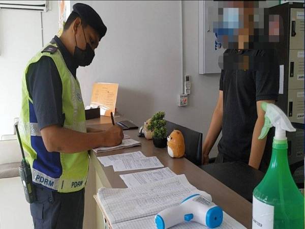 Anggota polis memeriksa buku pendaftaran penginap di hotel berkenaan selepas tetap berdegil meneruskan operasi setelah dikenakan kompaun pada malam Rabu.