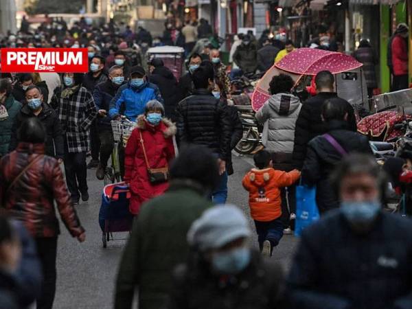 Orang ramai yang memakai pelitup muka berjalan di sebatang jalan di bandar raya Wuhan pada 19 Januari lalu. - Foto AFP