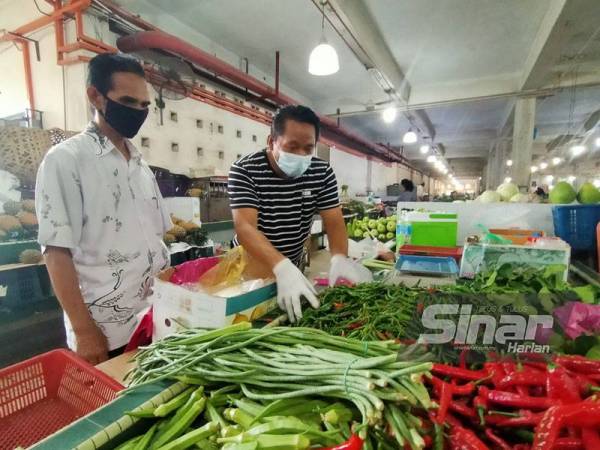 Mohd Fauzi melihat Mawardi menyusun sayur-sayurannya di Pasar Besar Alor Setar pada Jumaat.