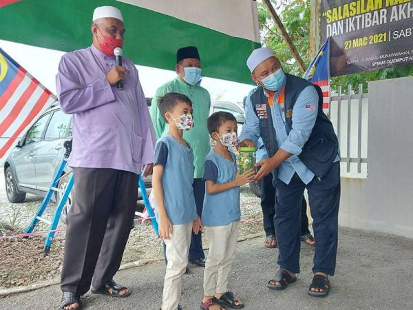 Muhammad Hakeem dan Muhammad Harith menyerahkan tabungan wang syiling yang dikumpul mereka kepada Muslim Care Malaysia.