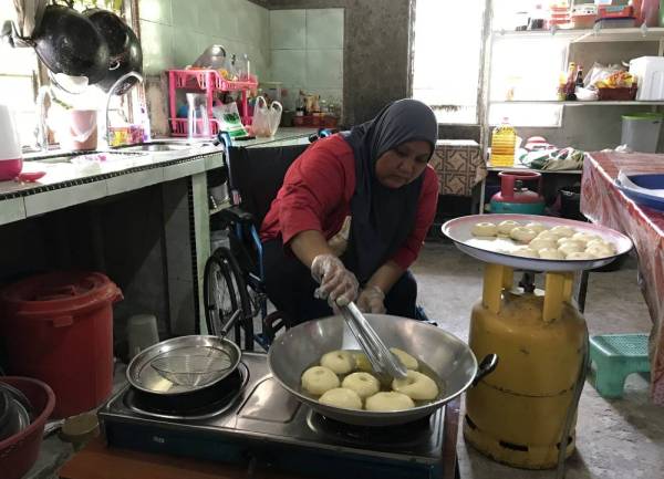 Suriati tetap gigih membuat kuih donut walaupun keterbatasannya bergerak akibat kemalangan jalan raya yang dialami pada tahun 2012 dan 2020 ketika ditemui di rumahnya di Kampung Batu Karang, Pasir Mas pada Sabtu. - Foto Bernama