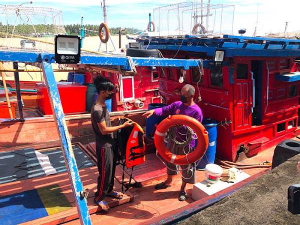 Hazahar dan Muhammad Iqram menunjukkan jaket keselamatan dan pelampung yang digunakan mangsa kelima ketika ditemui terapung di perairan Pantai Cahaya Bulan.