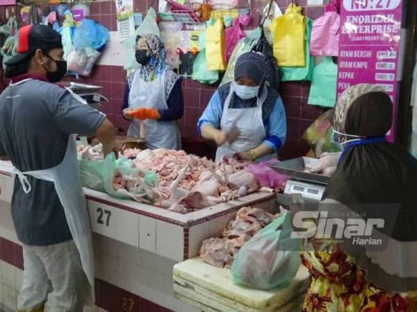 Azizah melayan pengunjung yang datang ke gerai ayam di Pasar Besar Kuantan pada Ahad.