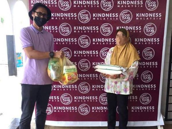 Mohd Azrul (kanan) menyerahkan bekalan makanan kepada penduduk terputus bekalan makanan di Food Bank Malaysia di Jalan Sultanah di Alor Setar.