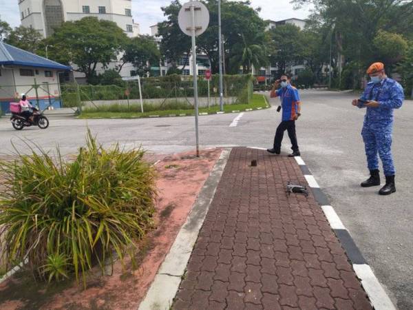 Ahmad Muafiri (kanan) sedang mengawal dron untuk meninjau sekitar kawasan Pusat Perdagangan Greentown, di sini, bagi melihat pematuhan orang ramai terhadap pematuhan SOP dengan kerjasama polis pada Isnin.