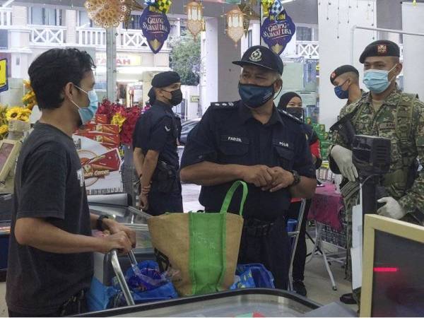 Mohd Fadzil (tengah) menyapa orang ramai di sebuah pasar raya semasa melakukan pemantauan pematuhan SOP di Jalan Diplomatik Presint 15 malam tadi. - Foto Bernama