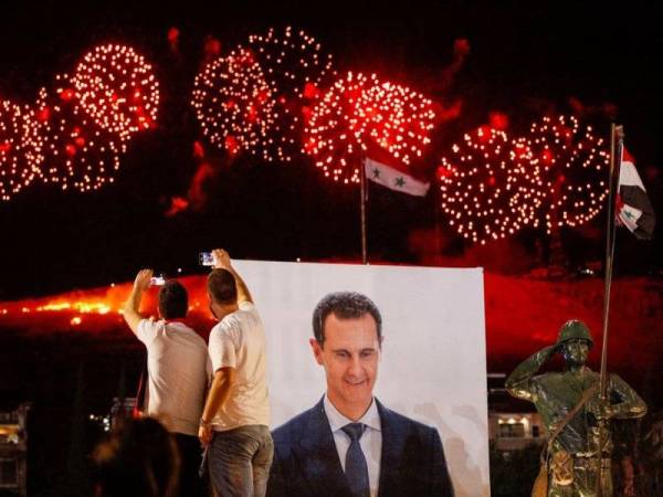 Penyokong Presiden Syria Bashar al-Assad meraikan kemenangan setelah keputusan pilihan raya presiden mengumumkan bahawa Bashar menang untuk penggal keempatnya. - Foto Reuters