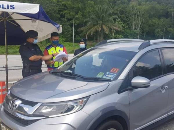 Arifai (kiri) melakukan pemeriksaan teliti terhadap pengguna lebuh raya di Plaza Tol Gombak pada Sabtu.