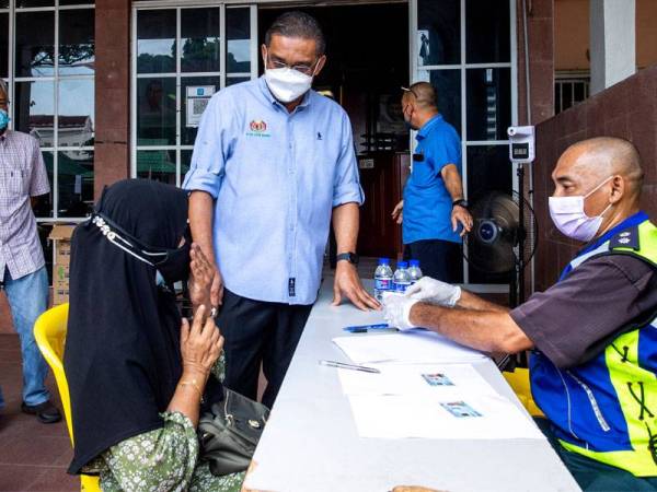 Takiyuddin Hassan (tengah) beramah mesra dengan penerima sumbangan, Rosnah Ab Razak,70, pada majlis saguhati untuk warga Parlimen Kota Bharu yang telah menerima suntikan vaksin di Pusat khidmat Ahli Parlimen Kota Bharu hari ini. -Foto Bernama