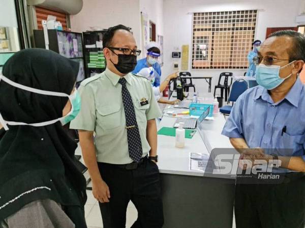 Dr Azman (kanan) diberi taklimat ringkas oleh pegawai perubatan ketika meninjau operasi Pusat Pemberian Vaksin (PPV) Klinik Kesihatan Klinik Kesihatan Kuala Kedah.