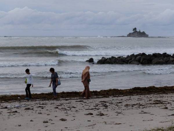 Para pengunjung tetap melakukan aktiviti riadah biarpun angin kencang dan laut bergelora ketika tinjauan di pantai Layang-layangan Labuan hari ini. - Foto Bernama