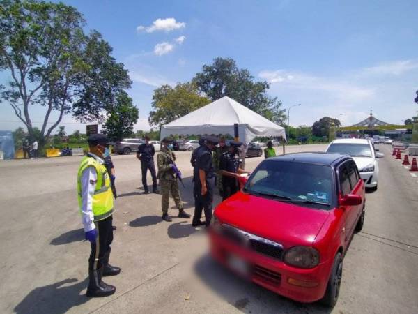 Mohd Roze (kanan) sedang memeriksa dokumen yang dibawa oleh seorang pemandu yang melalui SJR di Plaza Tol Alor Setar Utara di sini pada Rabu.