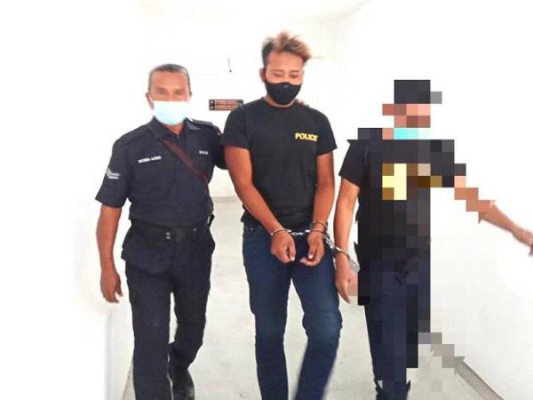 Mohamad Shafirul (tengah) dikawal polis menuju ke Mahkamah Sesyen Kota Bharu pada Khamis bagi berdepan tuduhan menetak seorang lelaki menggunakan sebilah pedang samurai.