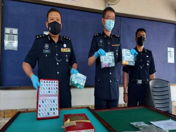 A Asmadi (kiri) menunjukkan jim rami batu yang dirampas daripada suspek yang disyaki melakukan aktiviti judi di Kampung Simee, Ipoh pada Khamis.