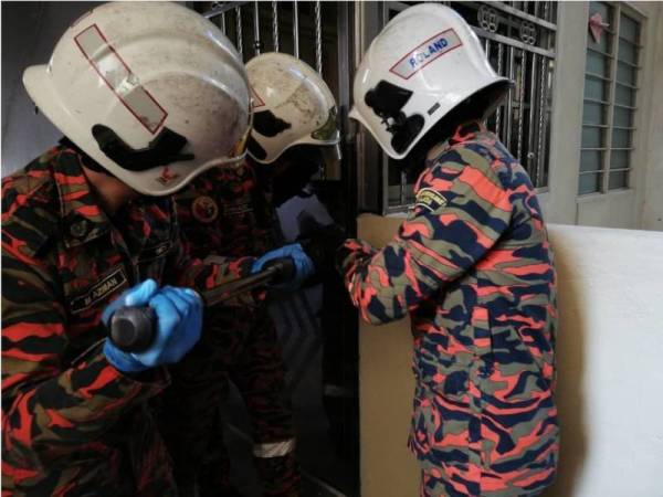 Anggota bomba dari Balai Bomba dan Penyelamat Larkin, Johor Bahru berusaha membuka pintu hadapan kediaman mangsa. Foto Bomba