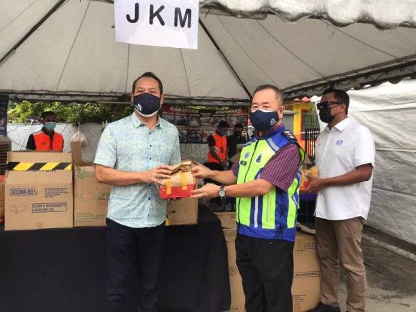 Ahmad Masrizal menyerahkan pek makanan kepada Ketua Polis Daerah Sentul, Asisten Komisioner Beh Eng Lai pada program penyerahan pek makanan di kawasan PKPD Sentul, pada Sabtu.