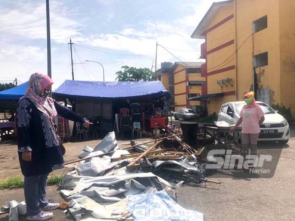 Nurihan (kiri) menunjukkan khemah gerai makannya di hadapan flat tersebut ranap dipukul ribut petang Sabtu. - FOTO SINAR HARIAN