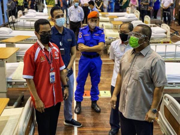 Muhammad Sanusi (kanan) membuat lawatan di Pusat Kuarantin dan Rawatan Covid-19 di Dewan Al Farabi, Kompleks Pendidikan Jalan Stadium di sini pada Isnin.