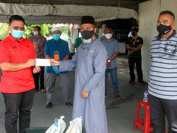 Syed Abu Hussin Hafiz (tengah) menyerahkan cek elaunnya bernilai RM105,000 kepada Pegawai Daerah Larut Matang dan Selama Mohamed Akmal Dahalan (kiri) sambil diperhatikan Ketua Polis Daerah Taiping ACP Osman Mamat (kanan) ketika ditemui di Taman Berkat di sini hari ini. -Foto Bernama