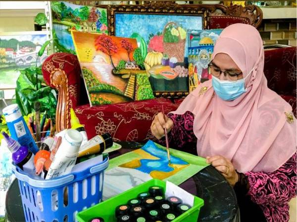 Fatmawati tekun menyiapkan lukisan ketika ditemui pemberita di rumahnya di Kampung Bunut Payong di sini. - Foto Bernama