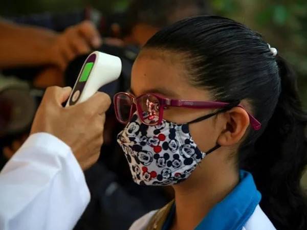 Suhu badan seorang murid diperiksa sebelum dia dibenarkan memasuki sekolah di bandar raya Mexico pada Isnin lalu. - Foto: AFP