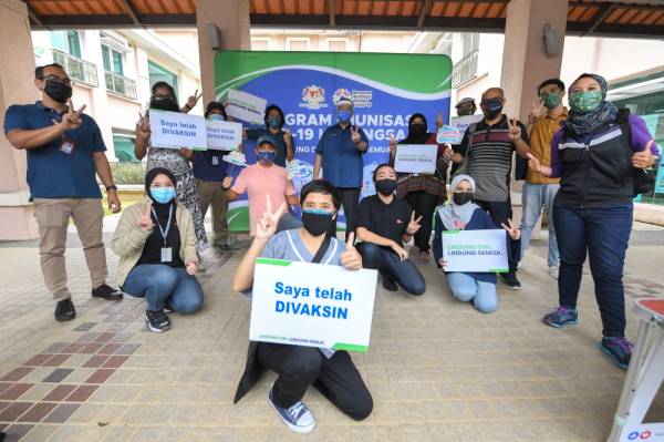 Menteri Komunikasi dan Multimedia Datuk Saifuddin Abdullah (berdiri, tengah) bergambar bersama sebahagian pengamal media yang telah menerima vaksin pertama pada tinjauan pemberian Vaksin Covid-19 kepada petugas media di Dewan Seri Seroja hari ini. -Foto Bernama