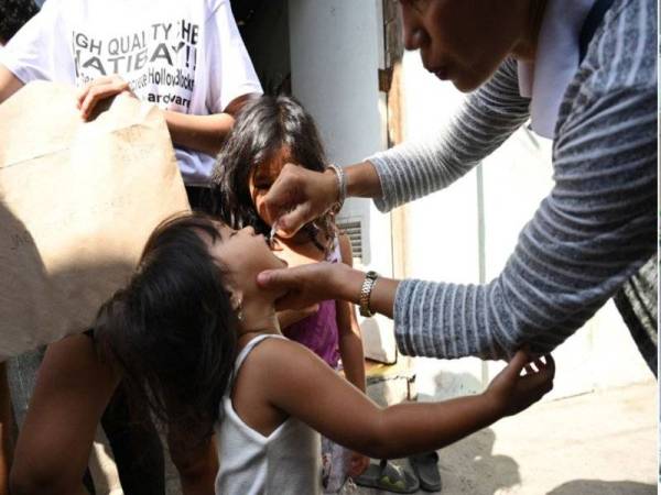 Seorang kanak-kanak perempuan diberikan vaksin polio semasa program imunisasi di Manila pada 2019. - AFP