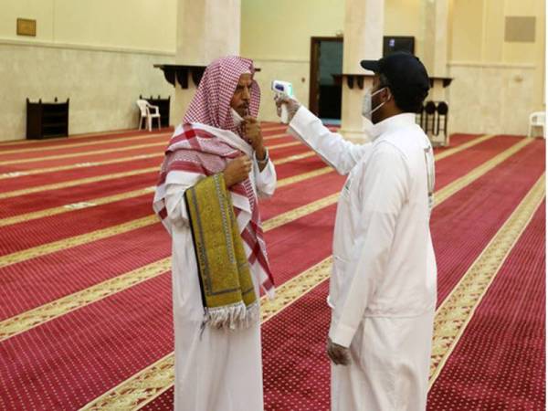 Sukarelawan memeriksa suhu badan seorang jemaah masjid sebelum dia menunaikan solat di sebuah masjid di Makkah, Arab Saudi. - Foto AFP