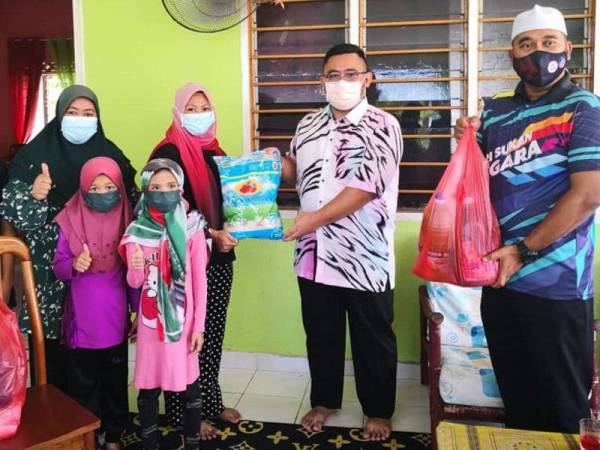 Shahrizal (dua dari kanan) menyampaikan bantuan kepada Normala yang turut disertai Nora di Kampung Tali Air 7, Sungai Leman, Sabak Bernam pada Khamis.