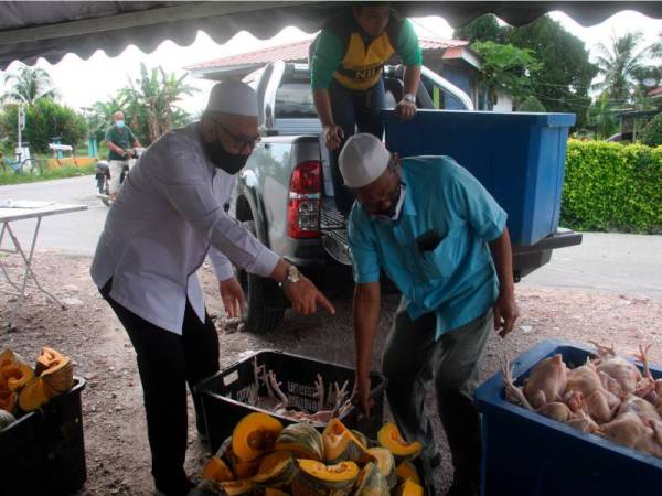 Razman (kiri) sedang memeriksa beberapa bantuan berupa ayam, labu manis dan limau yang akan diserahkan pada Penyerahan Sumbangan Keperluan Dapur Secara Pandu Lalu kepada penduduk di tiga buah kampung di Alor Setanggok, Gunung Semanggol dekat Bagan Serai pada Jumaat. - Foto Bernama