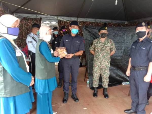 Maziah (dua dari kiri) menyampaikan sumbangan Rumah Ngaji Teluk Muroh kepada petugas barisan hadapan sebagai tanda penghargaan di sekatan jalan raya sekitar daerah Manjung pada Jumaat.