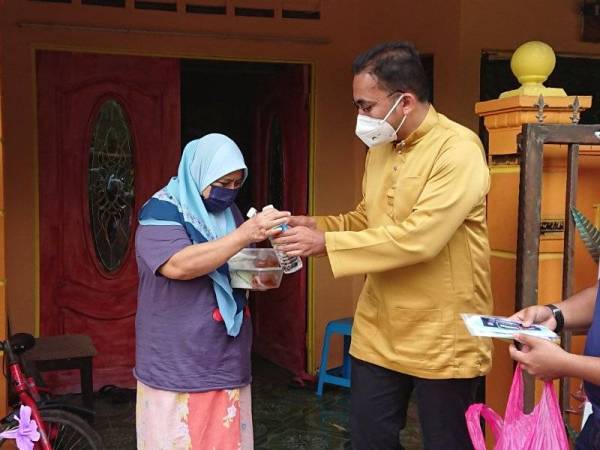 Mohd Rafiq (dua dari kanan) menyampaikan kotak makanan tengah hari kepda seorang penduduk di Taman Krubong Jaya, di sini, pada Ahad.