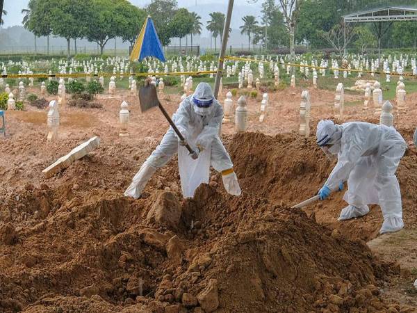 Petugas pengurusan jenazah melakukan kerja-kerja pengebumian jenazah pesakit Covid-19 di Tanah Perkuburan Islam Taman Selatan di Presint 20, Putrajaya baru-baru ini.  -Foto Bernama