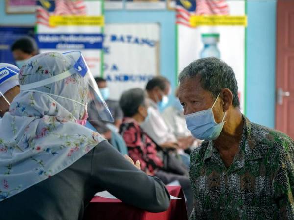 Apen mendapatkan penerangan lebih lanjut mengenai vaksin Covid-19 daripada kakitangan kesihatan bertugas sebelum menerima suntikan pertamanya sempena Program Pemberian Vaksin Bergerak di Balairaya Kampung Orang Asli Lubuk Bandung dekat Simpang Bekoh hari ini. - Foto Bernama