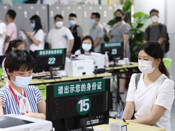 Seorang kakitangan mendaftarkan maklumat penerima vaksin Covid-19 di laman inokulasi Taman Perindustrian E-Dagang Antarabangsa Guangyi di Haizhu, Guangzhou. - Foto Xinhua