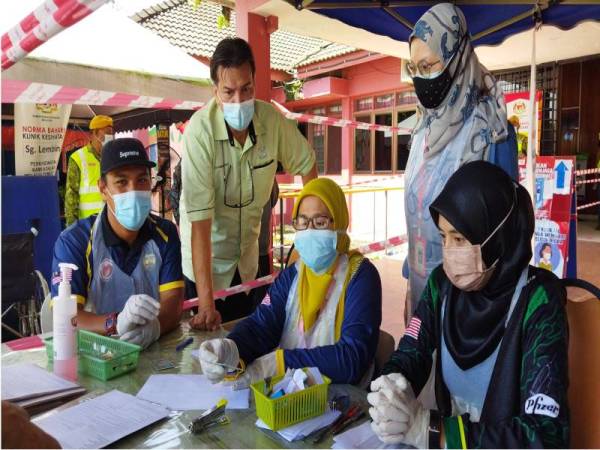 Muhammad Ridzal (berdiri) turut membantu kakitangan Klinik Kesihatan Sungai Lembing bagi menjayakan program vaksinasi Covid-19 kepada penduduk Sungai Lembing di klinik itu yang bermula pada Sabtu.