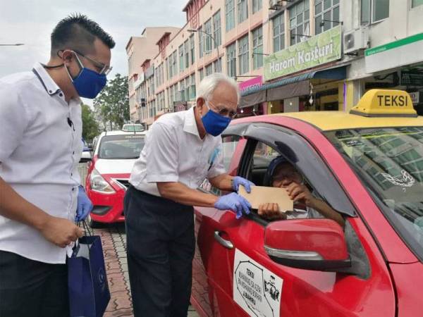 Shahrir (tengah) diiringi Mohd Hairi menyampaikan sumbangan kepada pemandu teksi dan e-hailing di hadapan Bangunan UMNO Bahagian Johor Bahru, Taman Suria, Johor Bahru pada Ahad.