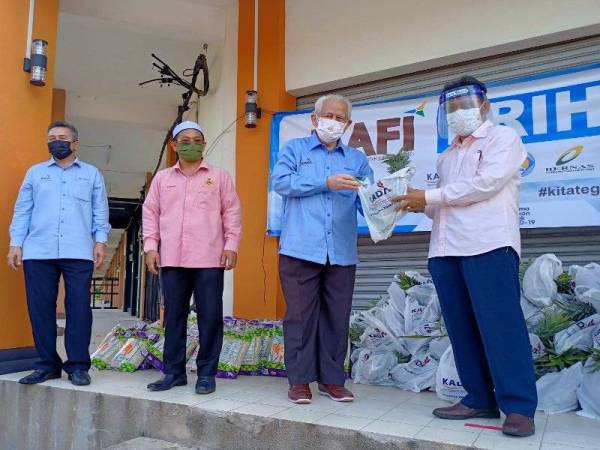 Che Abdullah (kanan) menerima sumbangan makanan daripada Kamarudin (tiga dari kiri) pada program bantuan MAFI Prihatin kepada penduduk di kawasan PKPD Taman Perumahan Merbau Utama, Selising, Pasir Puteh pada Ahad.