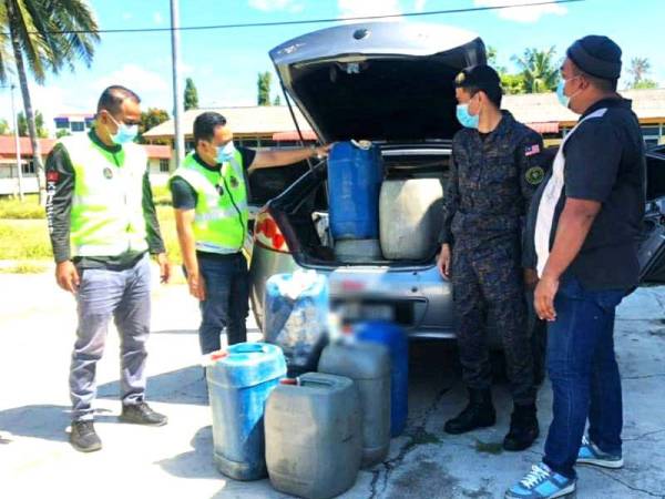 Anggota penguat kuasa memeriksa tong berisi petrol yang dipercayai cuba diseludup ke negara jiran dalam serbuan di Kampung Belukar, Wakaf Bharu, Tumpat pada Sabtu.