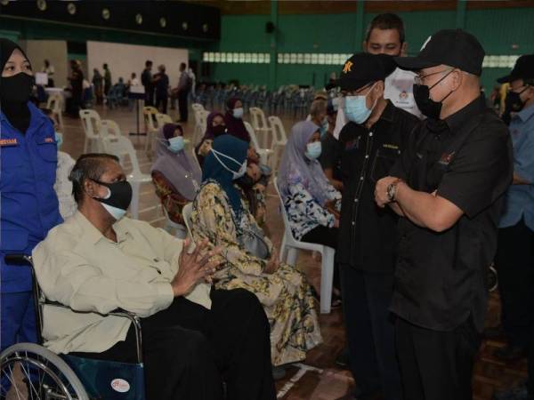 Ronald (kanan) beramah mesra dengan penduduk setempat yang menerima vaksin Covid-19 ketika melawat pusat pemberian vaksin dan menyampaikan sumbangan kotak makanan Kementerian Pertanian dan Industri Makanan (MAFI) Prihatin kepada penduduk Pagoh yang terkesan akibat pandemik Covid-19 di Kompleks Sukan Pagoh, pada Selasa. - Foto Bernama 