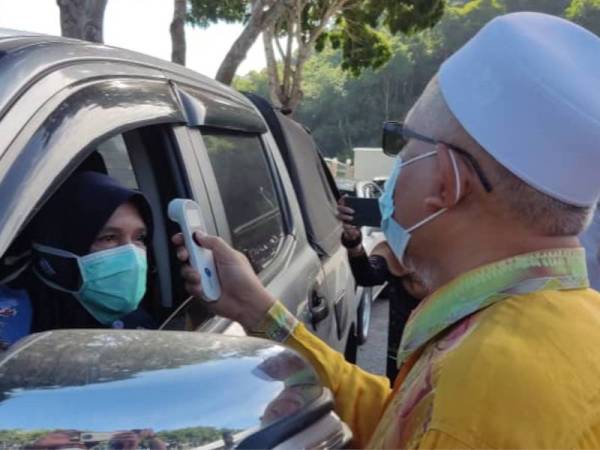 Mohd Hayati (kanan) membuat pemeriksaan suhu ke atas penerima vaksin pandu lalu, Umi Kalsom Mahmud, 51 di pekarangan Pejabat Daerah Padang Terap pada Khamis.