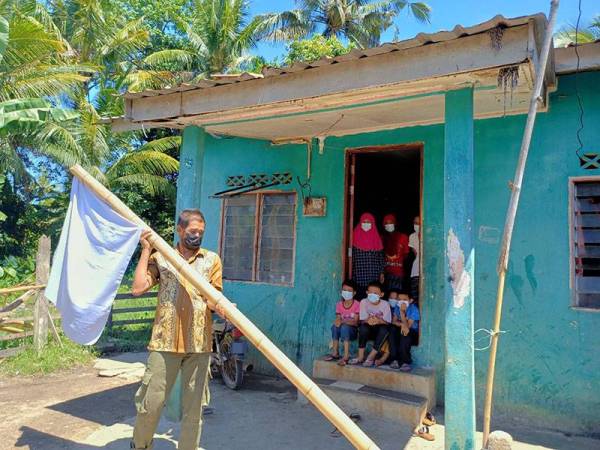 Zaidi memasang bendera putih di hadapan rumahnya di Kampung Banggol, Gelang Mas sambil diperhatikan oleh isteri, anak-anak dan cucu-cucunya.