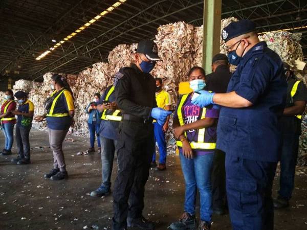 Mohd Azhar (kanan) ketika memeriksa aplikasi MySejahtera pekerja kilang tersebut sempena Op Patuh pada Jumaat