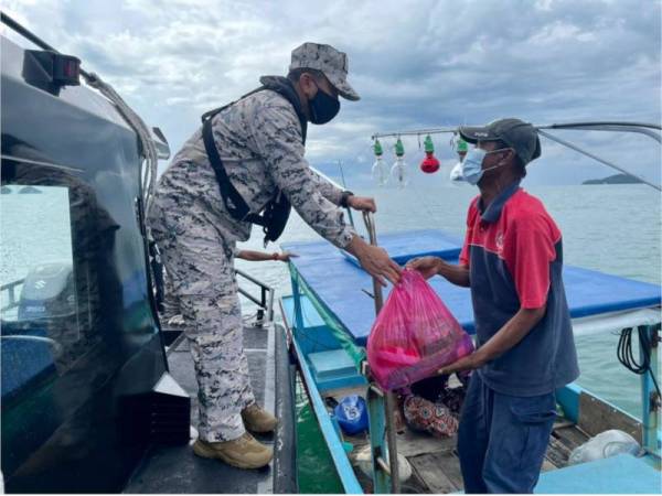 Mohd Zawawi (kiri) menyerahkan sumbangan keperluan kepada seorang komuniti nelayan di Langkawi yang terjejas akibat PKP 3.0. - Foto Maritim Malaysia