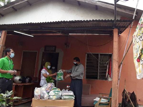 Mas Imran (kanan) menyerahkan bantuan berupa makanan asas kepada Ruzaitunsansuria di kediamannya di Kampung Sungai Tiram, Ulu Tiram, Johor Bahru pada Jumaat.